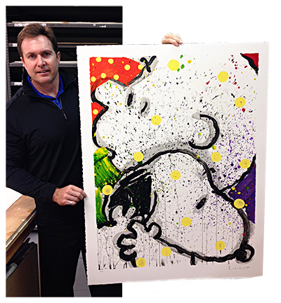 Tom Doyle at the Rue Royale Warehouse holding up a Peanuts, Snoopy lithograph